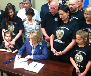 Governor Mary Fallin, joined by family members of Trooper Nicholas Dees and Trooper Keith Burch, signs HB1965.